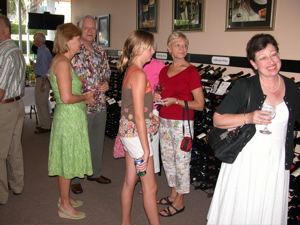 Sue Spitzer, left in the green dress, chats with well wishers during Thursday's grand opening and wine tasting.