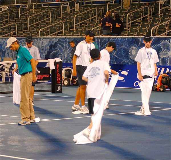 Tournament volunteers dry the court the old fashion way &mdash; with bags and bags of towels. 
