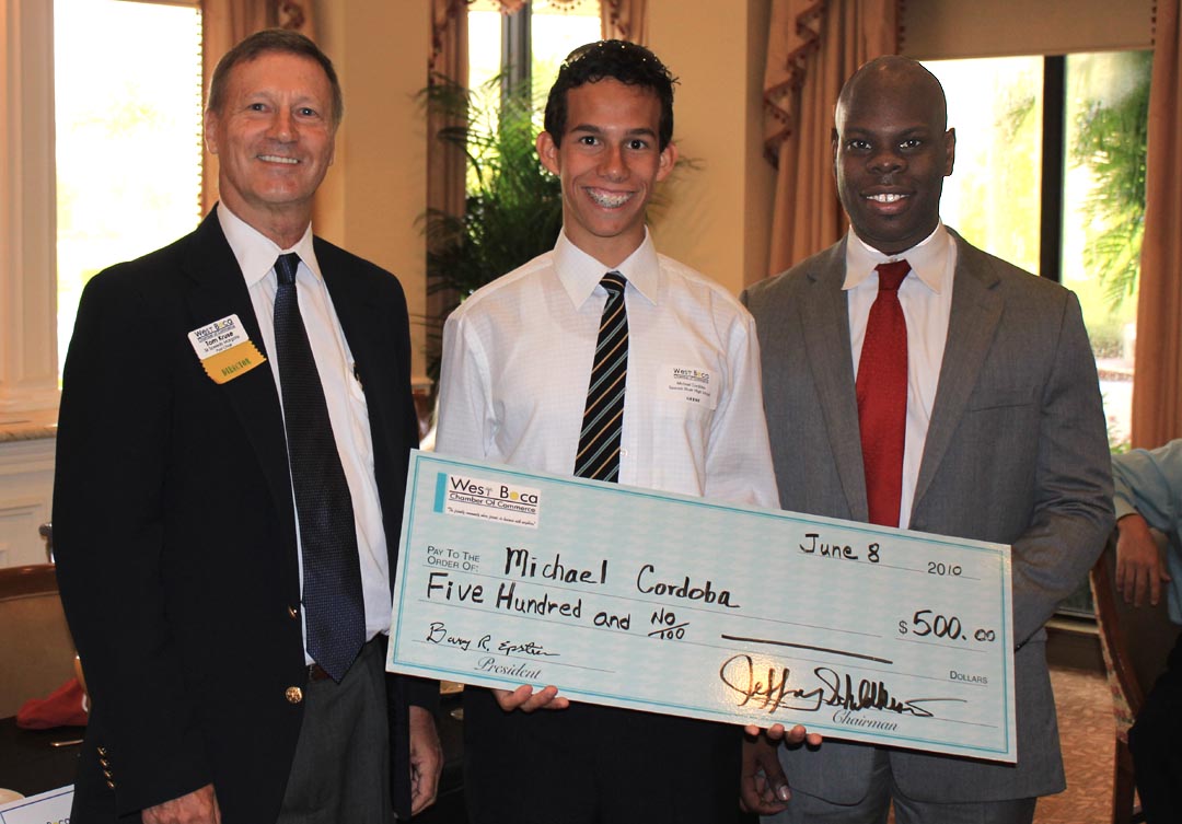 West Boca Foundation Chair Shelby Linton, right, and foundation Vice Chair Tom Kruse, left, present a scholarship check to Michael Cordoba. 